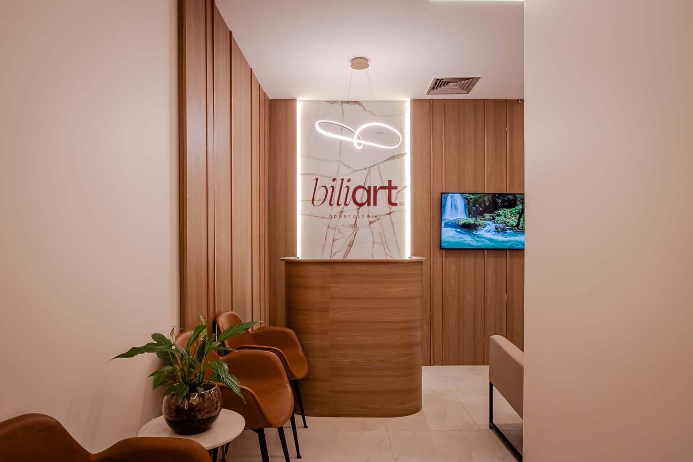 Recepção da Biliart, com poltronas e o painel com o logo